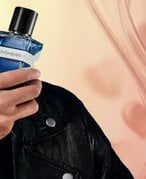 Man holding a bottle of Yves Saint Laurent cologne on a textured background