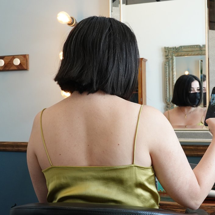 person with bob haircut looking at themselves in a mirror