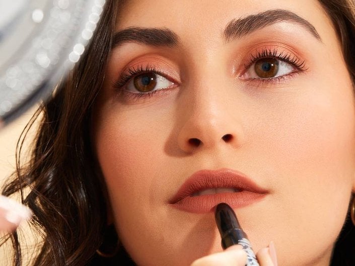 person applying lipstick in mirror