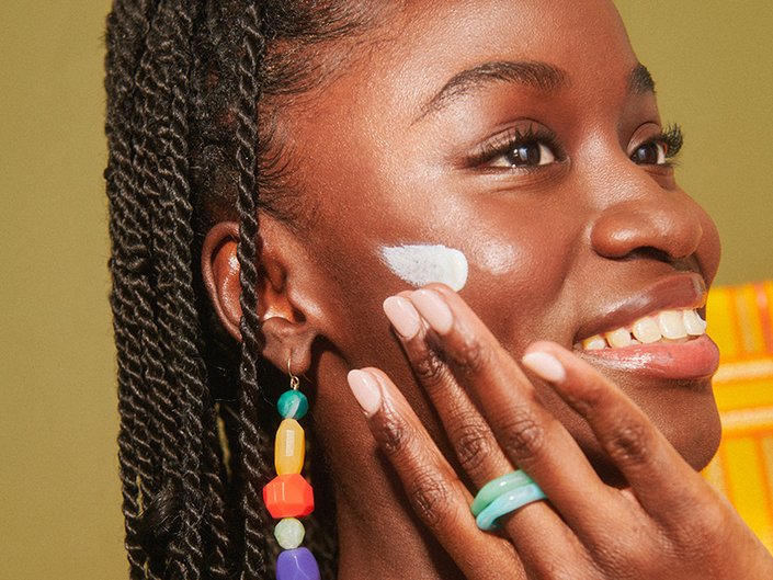 person applying sunscreen to cheek