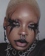 Picture of a person with goth makeup and piercings looking at the camera