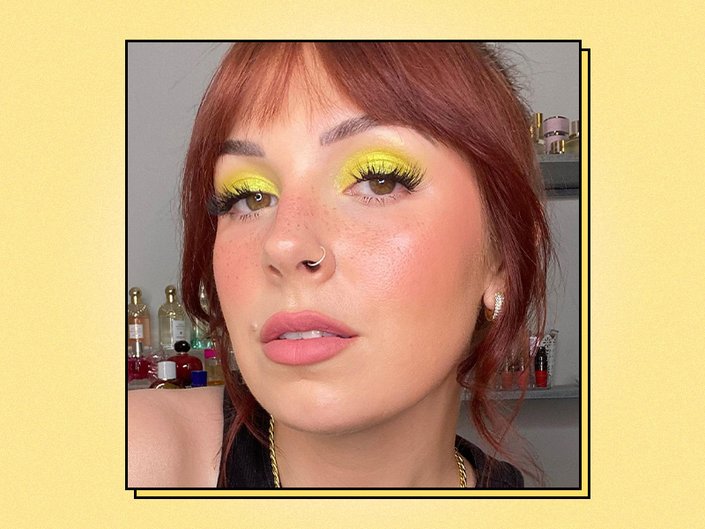 Picture of a person with hazel eyes and bright yellow eyeshadow on a graphic yellow background 