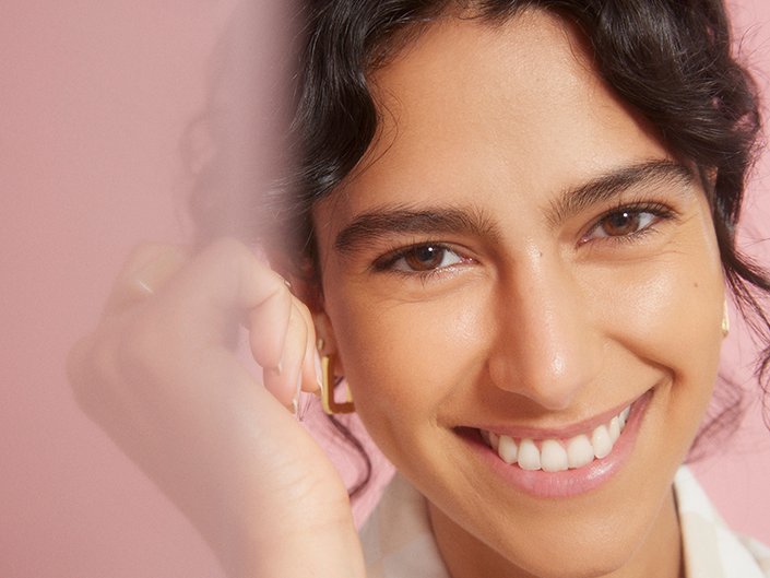 Picture of a model smiling against a pink background