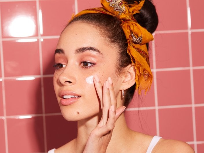 Photo of a person applying cream to their cheek