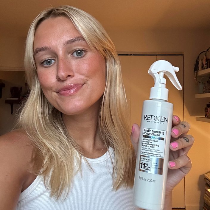 Editor with long blonde hair holding up the Redken Acidic Bonding Concentrate Lightweight Liquid