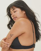 Picture of a person with long dark hair and a tattoo on their arm