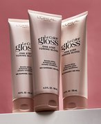 Three tubes of the L’Oréal Paris Le Color Gloss One Step In-Shower Toning Gloss against a red background