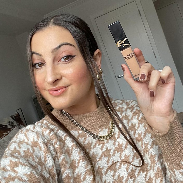 Alanna wearing and holding up the YSL Beauty All Hours Creaseless Precise Angles Concealer