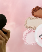 Woman looks into compact while applying pressed powder