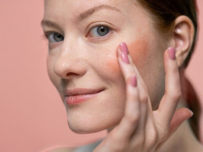 Photo of a person showing how to use lipstick as blush
